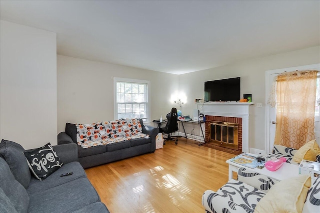 living room with a brick fireplace and hardwood / wood-style floors