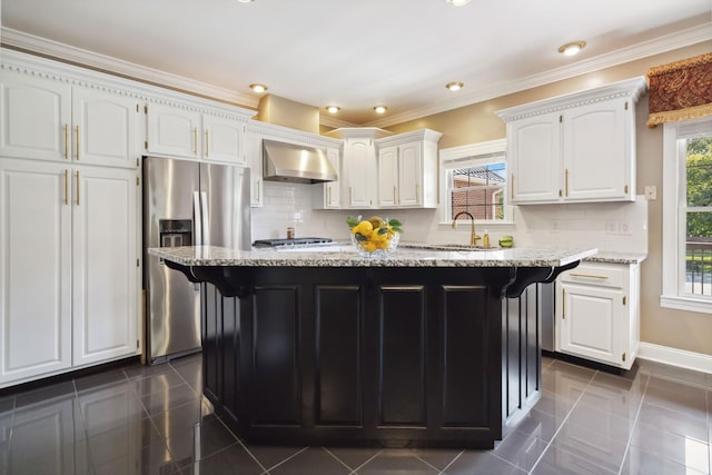 kitchen with wall chimney exhaust hood, white cabinets, stainless steel refrigerator with ice dispenser, light stone counters, and a sink