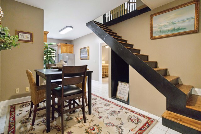 dining area featuring light tile patterned floors, baseboards, and stairway