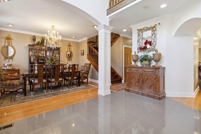 dining room featuring crown molding, decorative columns, arched walkways, stairs, and baseboards