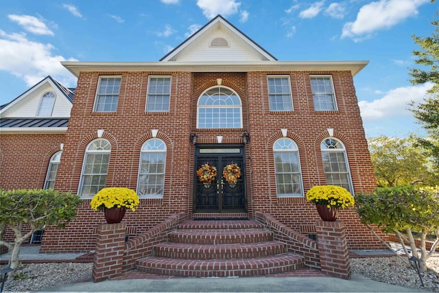 view of front facade with brick siding, metal roof, and a standing seam roof
