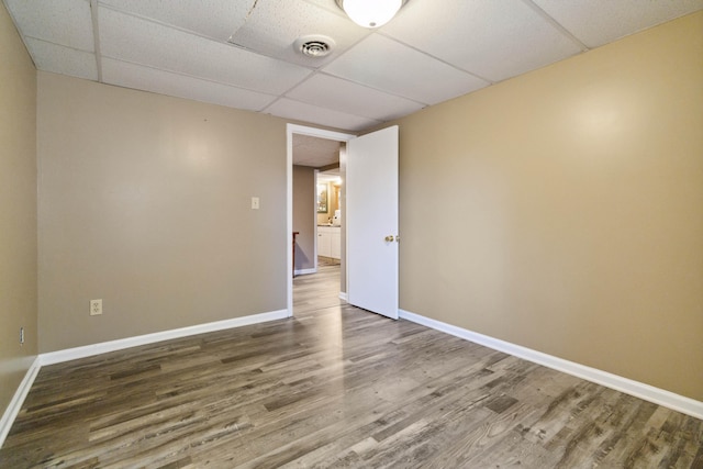 empty room with visible vents, baseboards, a drop ceiling, and wood finished floors