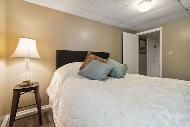 bedroom with wood finished floors, baseboards, and a drop ceiling