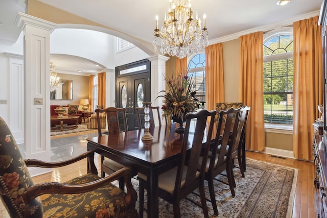 dining area with arched walkways, wood-type flooring, a notable chandelier, and ornamental molding