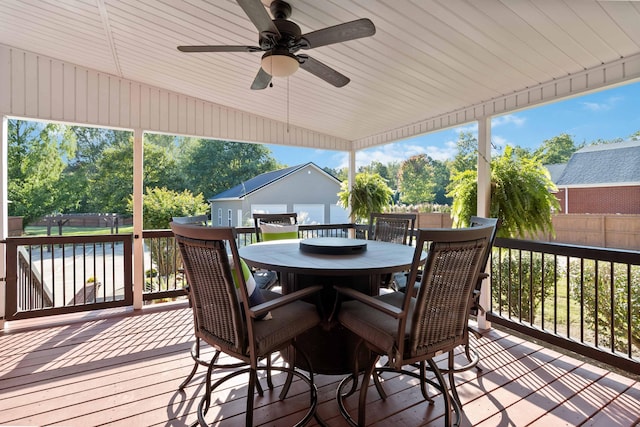wooden deck featuring outdoor dining space, an outdoor structure, fence, and ceiling fan