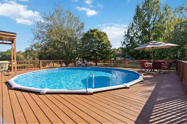 view of pool with outdoor dining space, a wooden deck, and a fenced in pool