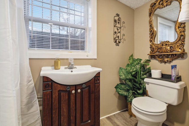 bathroom featuring toilet, wood finished floors, vanity, and baseboards
