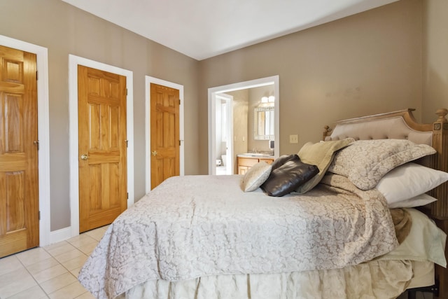bedroom with a sink, light tile patterned floors, baseboards, and ensuite bathroom