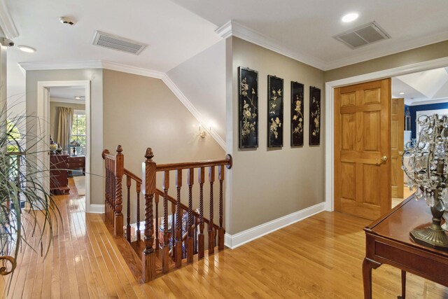 hallway featuring an upstairs landing, visible vents, light wood-type flooring, and crown molding
