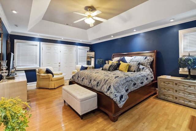 bedroom featuring visible vents, ornamental molding, a raised ceiling, and light wood-style floors