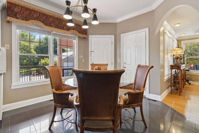 dining space with arched walkways, a notable chandelier, baseboards, and crown molding