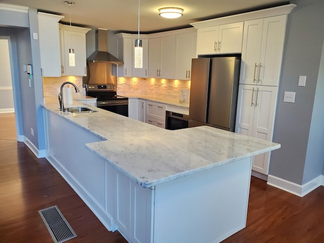 kitchen featuring stainless steel appliances, white cabinets, wall chimney exhaust hood, sink, and hanging light fixtures