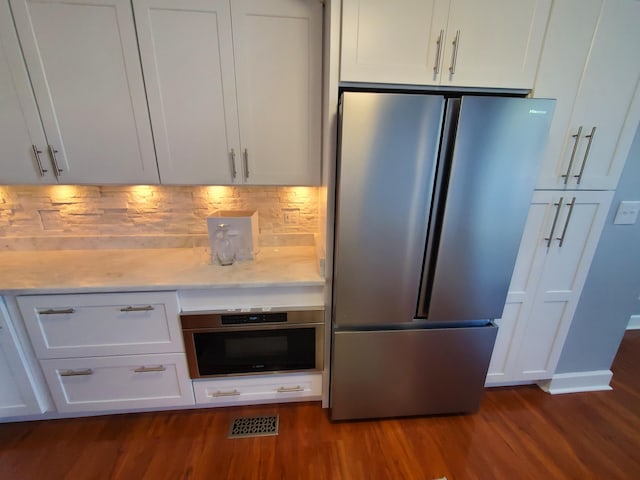 kitchen with dark hardwood / wood-style floors, backsplash, stainless steel appliances, and white cabinets