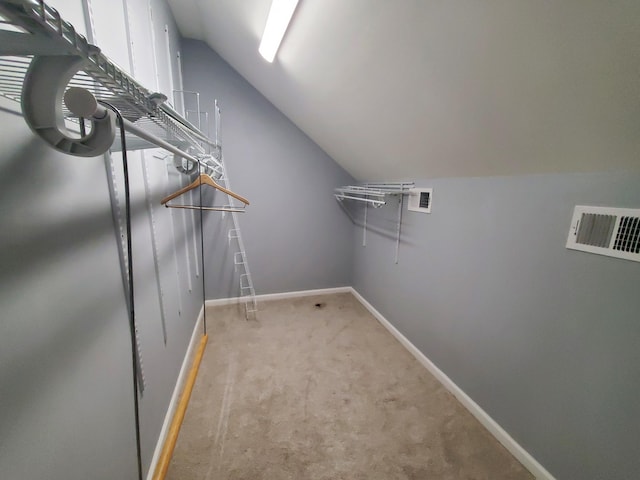 walk in closet featuring lofted ceiling and light colored carpet