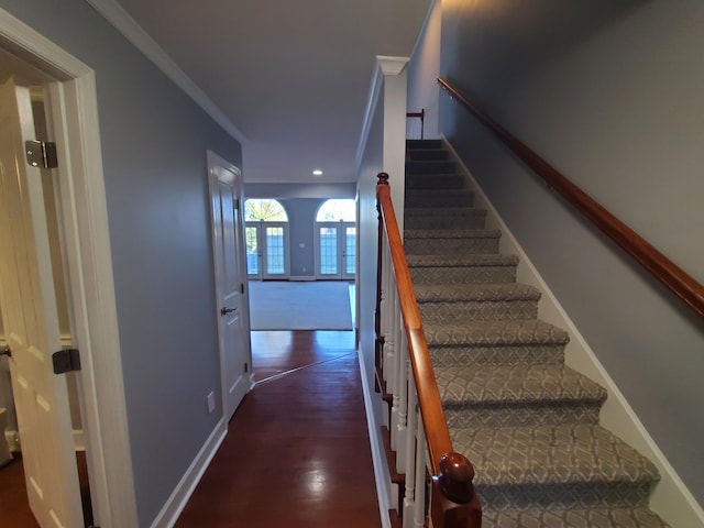 stairway with ornamental molding and hardwood / wood-style floors