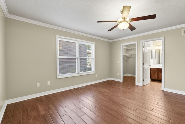 unfurnished bedroom featuring a spacious closet, a textured ceiling, hardwood / wood-style flooring, and ceiling fan