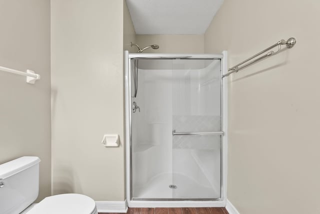 bathroom with a textured ceiling, hardwood / wood-style flooring, toilet, and walk in shower