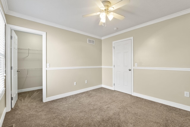 unfurnished bedroom featuring a spacious closet, ornamental molding, carpet floors, and ceiling fan