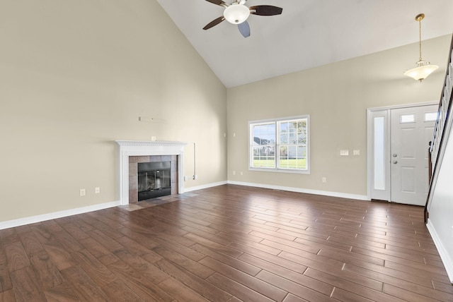 unfurnished living room with high vaulted ceiling, dark wood-type flooring, and a tile fireplace