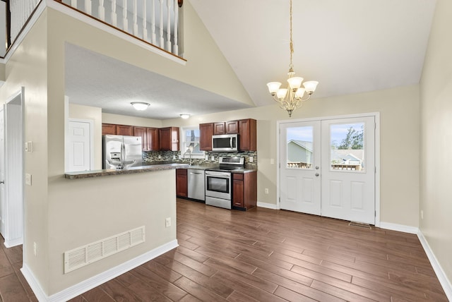 kitchen featuring hanging light fixtures, backsplash, dark hardwood / wood-style flooring, a chandelier, and stainless steel appliances