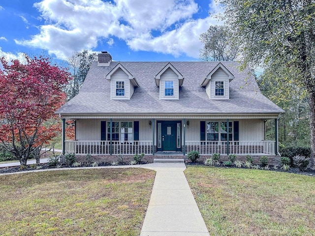 cape cod home with a chimney, covered porch, a shingled roof, and a front lawn