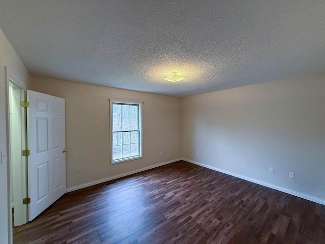 unfurnished room featuring dark wood finished floors, visible vents, a textured ceiling, and baseboards