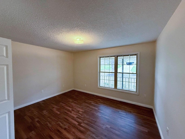 unfurnished room featuring a textured ceiling, dark wood-type flooring, and baseboards