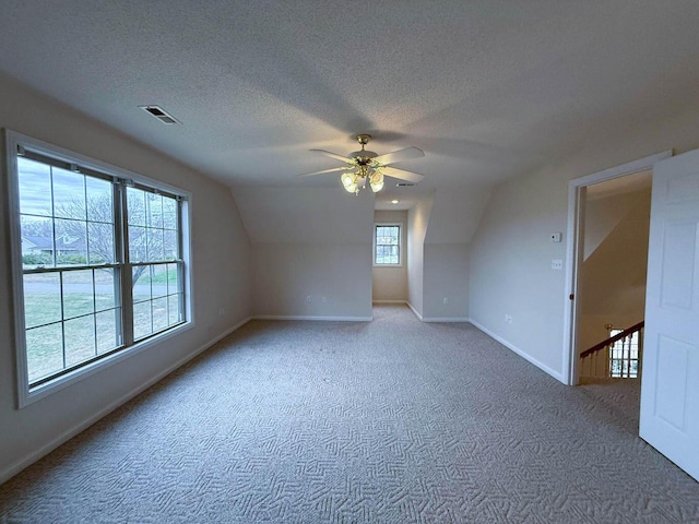 additional living space featuring visible vents, baseboards, a textured ceiling, and carpet flooring