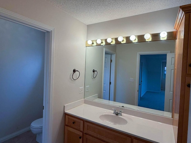 bathroom featuring vanity, toilet, baseboards, and a textured ceiling