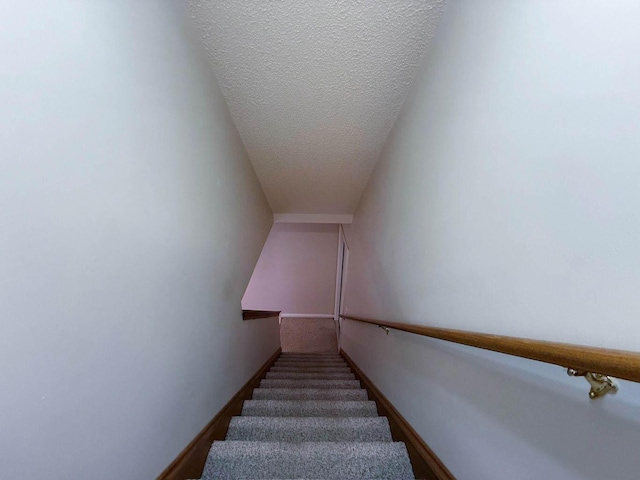 stairs with a textured ceiling and baseboards