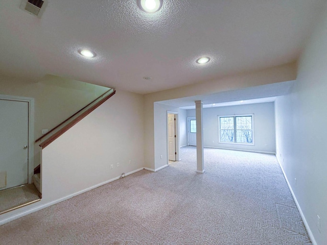 below grade area with visible vents, carpet floors, a textured ceiling, and stairway