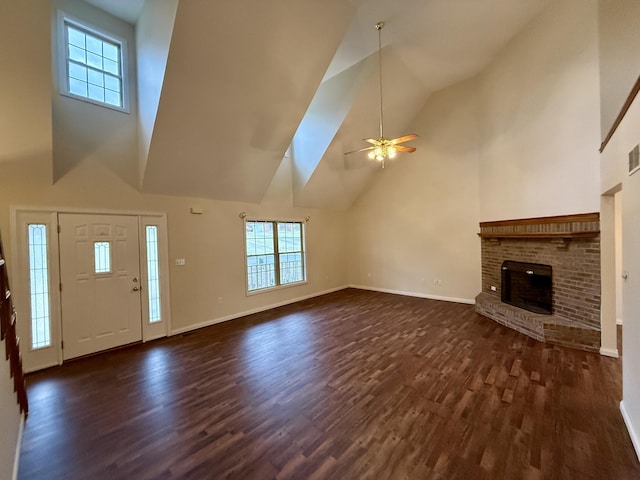 unfurnished living room featuring a brick fireplace, baseboards, dark wood-style floors, and a ceiling fan