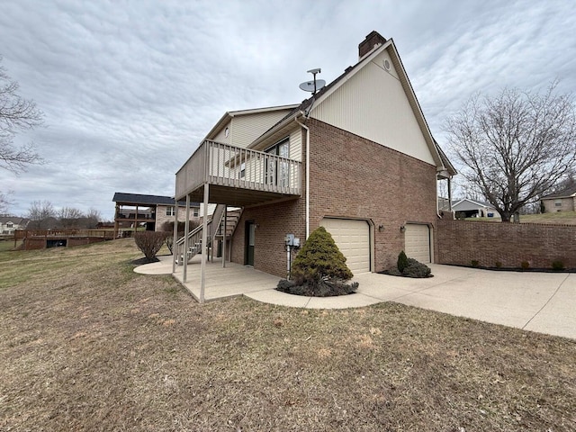 rear view of house with a chimney, stairs, concrete driveway, a garage, and brick siding