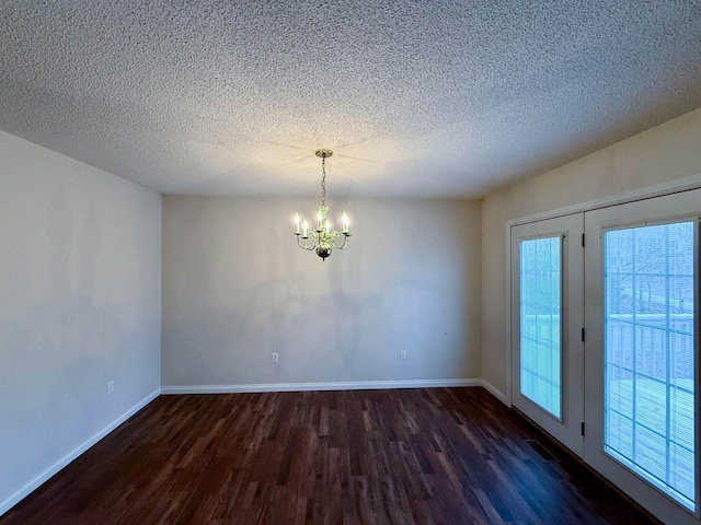 unfurnished room with a chandelier, a textured ceiling, baseboards, and dark wood-style flooring