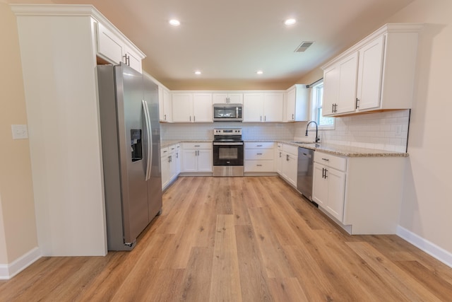 kitchen with stainless steel appliances, light wood-type flooring, sink, and white cabinetry