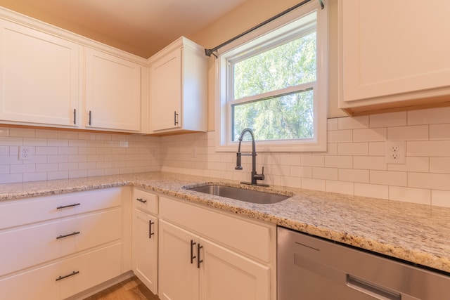 kitchen featuring stainless steel dishwasher, sink, decorative backsplash, and white cabinetry