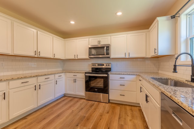 kitchen with light hardwood / wood-style flooring, sink, stainless steel appliances, and white cabinets