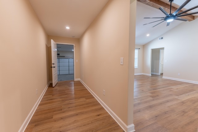 hall featuring lofted ceiling, a barn door, and light hardwood / wood-style flooring