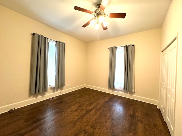 unfurnished bedroom with ceiling fan, a closet, and dark wood-type flooring