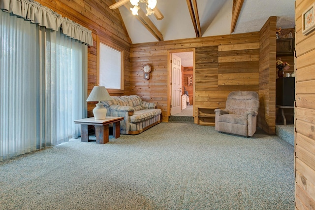 living area with ceiling fan, beamed ceiling, wooden walls, and carpet floors