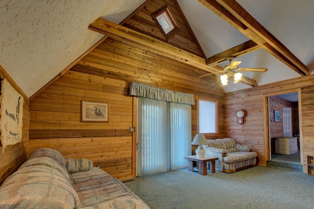 living room with wooden walls, carpet, ceiling fan, and beam ceiling