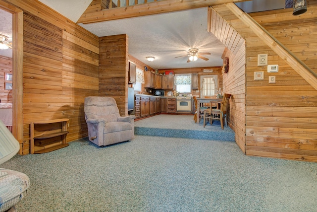 living room featuring wood walls, ceiling fan, a textured ceiling, and carpet floors