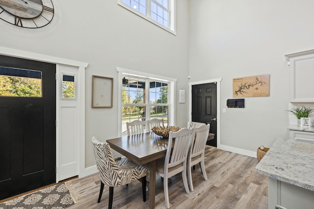 dining room with light hardwood / wood-style flooring and a towering ceiling