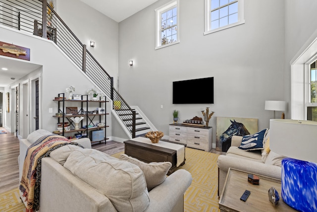 living room featuring a towering ceiling, plenty of natural light, and light wood-type flooring