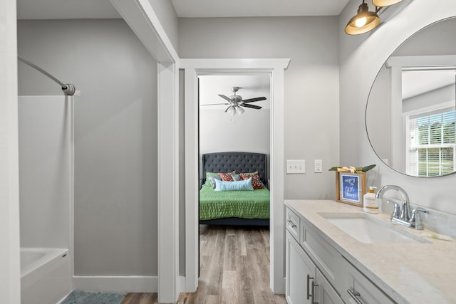 bathroom with hardwood / wood-style flooring, ceiling fan, washtub / shower combination, and vanity