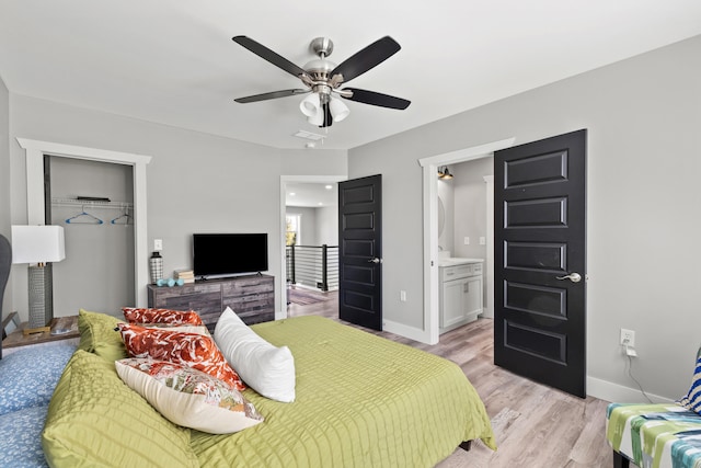 bedroom featuring ceiling fan, light hardwood / wood-style flooring, a closet, a spacious closet, and ensuite bathroom