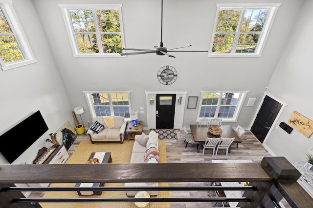 living room featuring ceiling fan, plenty of natural light, and a high ceiling