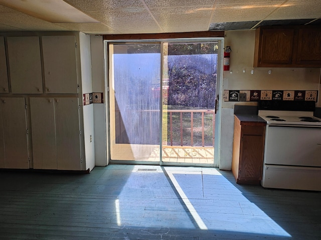 kitchen featuring a drop ceiling, light hardwood / wood-style floors, electric stove, and a healthy amount of sunlight