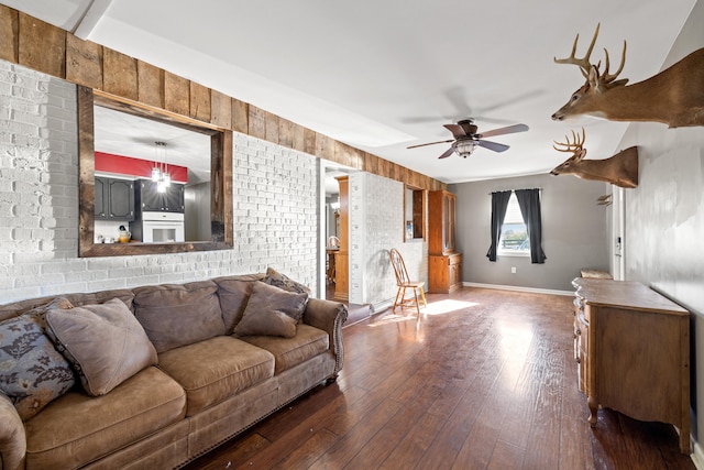 living room with wood walls, ceiling fan, and dark hardwood / wood-style flooring