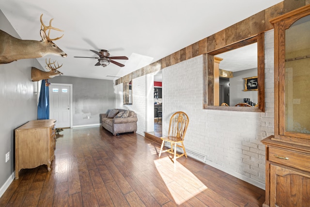 living area with brick wall, ceiling fan, and dark hardwood / wood-style flooring